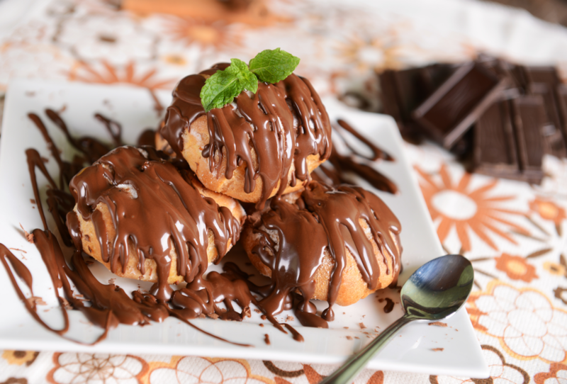 Bánh su kem Profiterole thường được nhúng thêm một lớp sốt socola giúp tăng hương vị ngọt béo cho chiếc bánh (Nguồn: Canva)