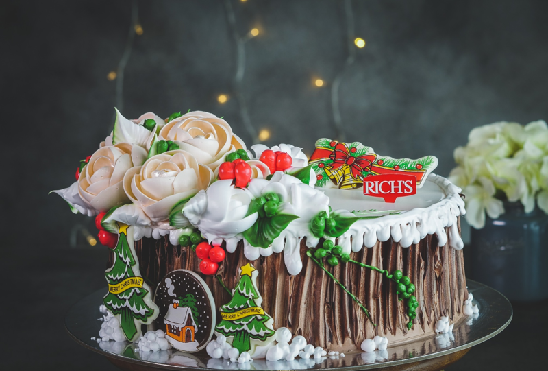 Chiếc bánh sẽ trở nên độc đáo hơn khi được tạo hình khúc gỗ và điểm xuyết thêm một vài bông hoa phía trên 