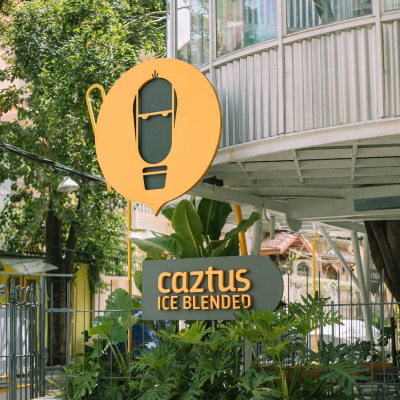 Caztus Ice Blended nổi bật với tấm bảng hiệu màu vàng tươi tắn trên nền xanh lá cây